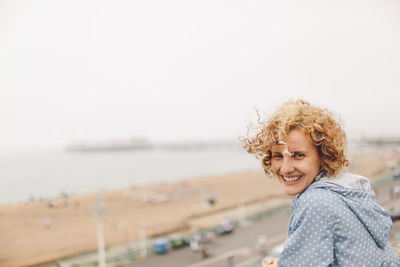 Portrait of happy woman against clear sky