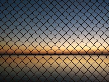 Scenic view of sea against sky seen through chainlink fence