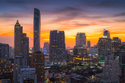 Modern buildings in city against sky during sunset