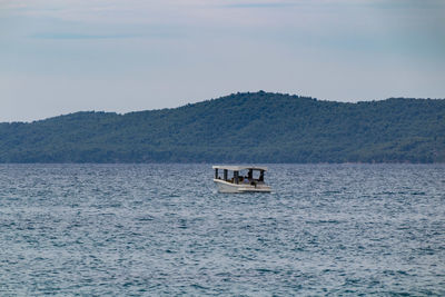 Boat sailing on sea against mountain