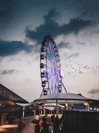 Low angle view of ferris wheel against sky at dusk