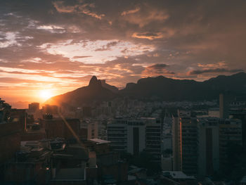 Buildings in city against cloudy sky during sunset