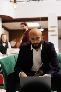 Portrait of young man using laptop at office