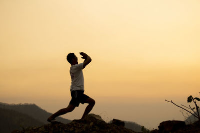 Rear view of man standing against sky during sunset