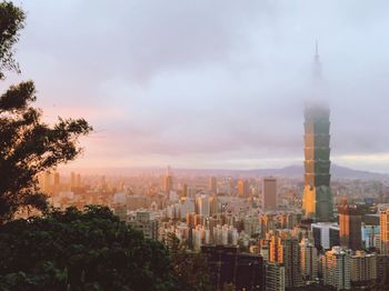 Buildings in city against cloudy sky