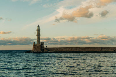 Lighthouse by sea against sky