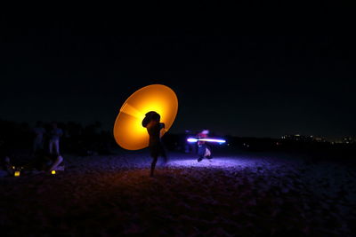 People on beach against clear sky at night