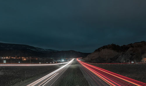 Road passing through field against cloudy sky