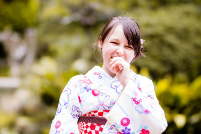 Portrait of smiling woman in kimono against trees