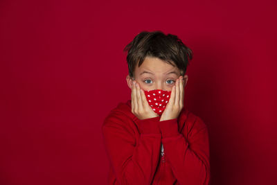 Portrait of man covering face against red background