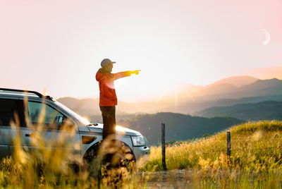 Rear view of woman with arms raised on field