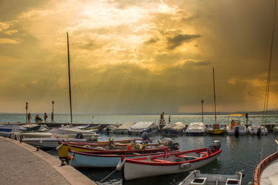 Boats moored in harbor at sunset