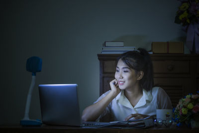 Young woman using mobile phone while sitting on table