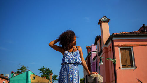 Low angle view of woman standing against blue sky