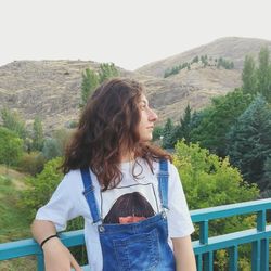 Woman standing by railing against mountain