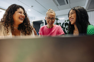 Happy multiracial businesswomen laughing at work place