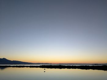 Scenic view of lake against clear sky during sunset