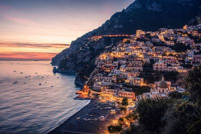 Aerial view of sea and cityscape against sky during sunset