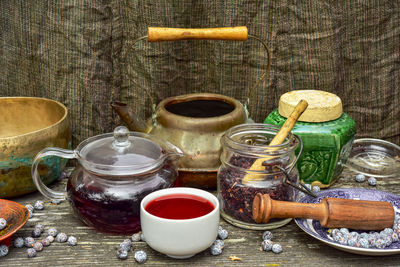 Rustic japanese copper tea kettle, jar of dried hibiscus flower tea, filled tea cup, juniper berries