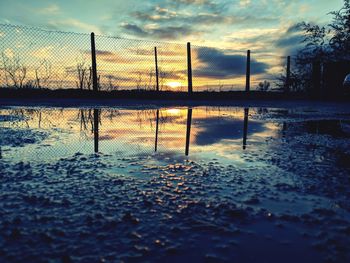 Reflection of silhouette trees in lake against sky during sunset