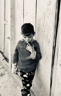 High angle view of boy standing on footpath against wall