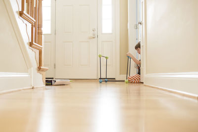 Young boy sits in sunny bright hallway playing with building toys