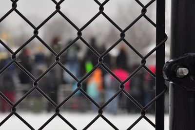 People seen through chainlink fence during winter