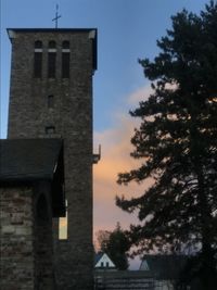 Low angle view of trees and building against sky