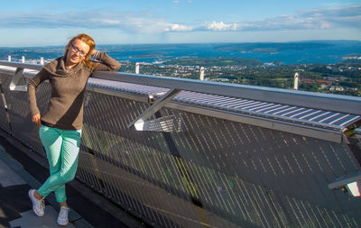 Portrait of young woman standing at holmenkollen ski arena against cloudy sky