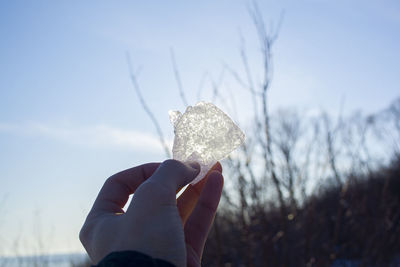 Close-up of person holding ice cream against sky