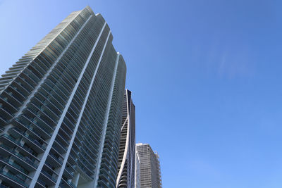 Low angle view of modern buildings against clear blue sky