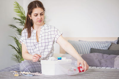 Young woman using mobile phone while sitting on bed at home