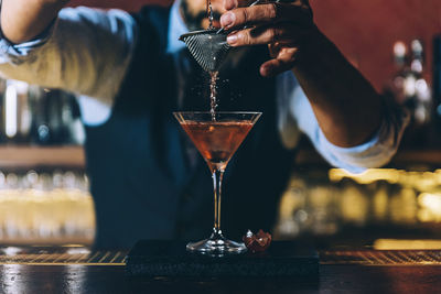 Midsection of bartender preparing cocktail in bar