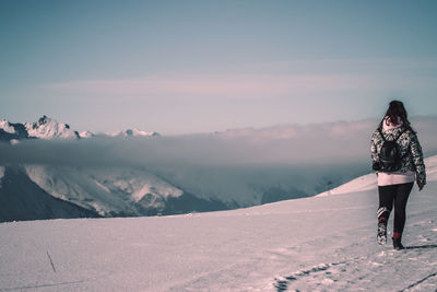 Man standing on snowcapped mountain against sky