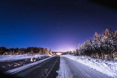 Snow covered road against clear sky at night