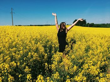 Woman with arms raised standing amidst flowers