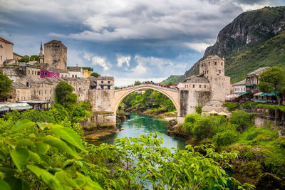 Arch bridge over river against cloudy sky