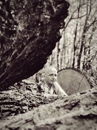 Portrait of man by tree trunk in forest