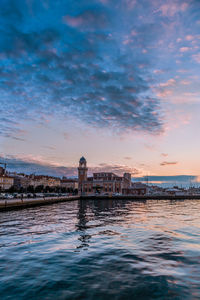 Reflection of building in sea at sunset