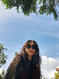 Portrait of young woman in sunglasses against sky