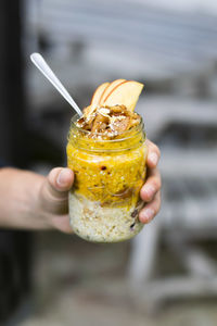 Cropped image of hand holding jar with apple porridge 