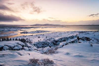 Scenic view of lake against sky during winter at sunset