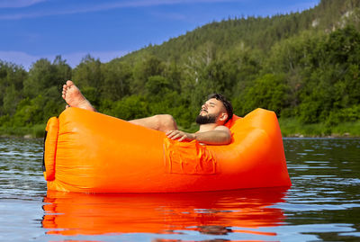 Man relaxing on boat against trees