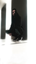 Portrait of young man sitting on floor against white background