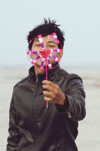 Portrait of young man holding pinwheel toy outdoors