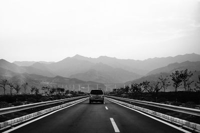 Road leading towards mountains against sky