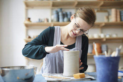 Young woman molding pot in art class