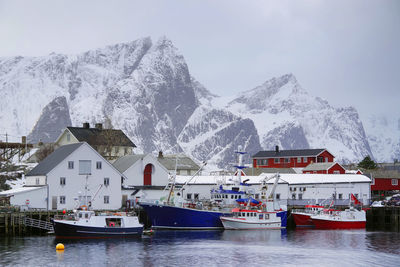 Buildings by snowcapped mountain against sky