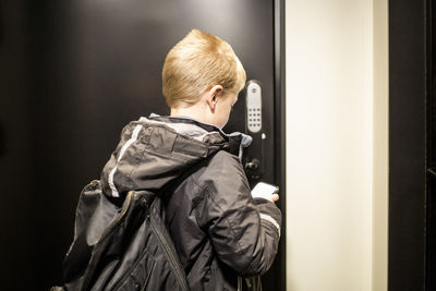 Rear view of boy using app on smart phone to unlock door