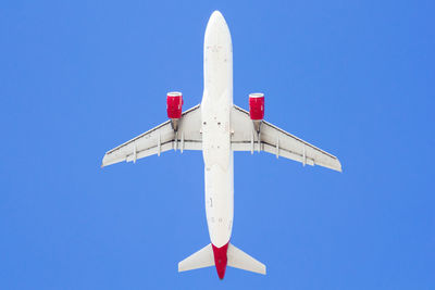 Low angle view of airplane flying against clear blue sky